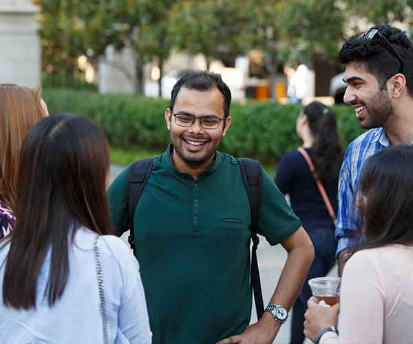 international students gather in an outdoor space happily speaking to one another